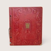 Vintage 1940s red embossed leather scrapbook with string binding and scroll motifs.