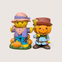 Vintage handpainted ceramic Halloween figurines of a scarecrow on pumpkins next to a jack o lantern holding a broom.