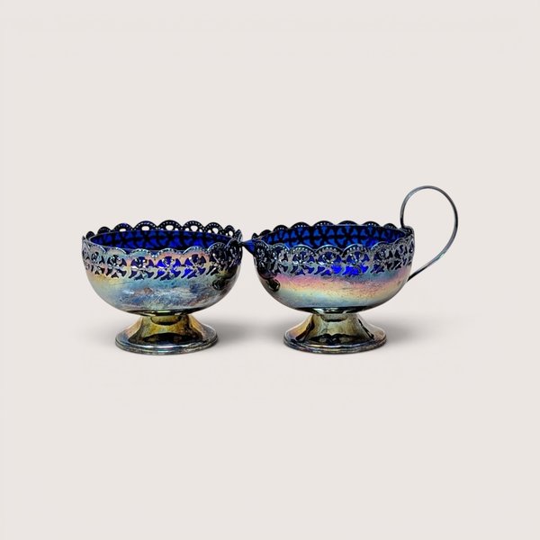 Ornate vintage English pierced silverplated cream and sugar set with vibrant cobalt blue glass liners.