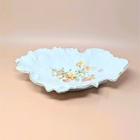Large, ornate Carl Tielsch porcelain bowl with a highly ruffled, scalloped edge and gold gilt trim. Features embossed scrollwork and a central transfer of autumnal wildflowers in peach, pink, and yellow.