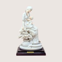 Vintage 1992 Giuseppe Armani porcelain figurine of a mother and child seated next to a floral sculpture on a wooden base.