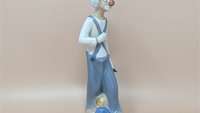 Slender Cascades Spanish porcelain figurine of a melancholic clown. Features a muted palette of slate grey and dusty blue with a high-gloss finish. Hand-painted details on the face and ruffles, 9.5 inches tall.