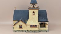Dept. 56 Seasons Bay "Chapel on the Hill." Miniature cream-colored stone chapel with a tall dark grey steeple, stained glass windows, and a cobblestone base. Matte finish porcelain.