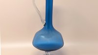 Mid-century hand-blown art glass decanter in a brilliant cobalt blue. Features a globular body, a long slender neck, and a clear twisted glass handle and pedestal base. 11 inches tall.