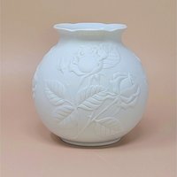 Kaiser West Germany white bisque porcelain vase with a globular body and flared rim. Features a high-relief embossed rose and leaf design with a soft matte finish. 5.5 inches tall.