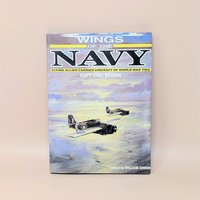 Hardcover book titled "Wings of the Navy" by Capt. Eric Brown. Dust jacket features a painting of two Allied fighter planes flying over a sunset-lit sea. 1987 edition.