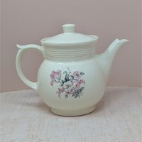 Vintage cream ceramic Drip-O-Lator coffee pot and lid. Features a central floral spray of pink tulips and white daisies. Sculptural scroll-top handle and tiered "stepping" on the neck. 7.25 inches tall.