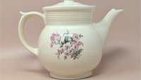 Vintage cream ceramic Drip-O-Lator coffee pot and lid. Features a central floral spray of pink tulips and white daisies. Sculptural scroll-top handle and tiered "stepping" on the neck. 7.25 inches tall.