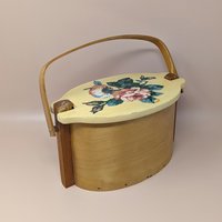 Vintage Basketville wood bucket with a swing handle and fitted lid. Features a hand-painted pink rose and blue floral bouquet on a cream-colored lid. Natural light wood finish. 11.5 inches long.