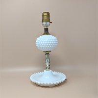 Vintage white milk glass lamp with a hobnail texture. Features a central hobnail globe and a wide, beaded tray base. Brass-tone hardware. 11.5 inches tall.