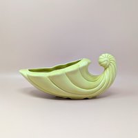 Vintage mid-century cornucopia planter in a soft pastel yellow. Features a sculptural "horn of plenty" design with swirled ridges and a curled tail. 11 inches long.
