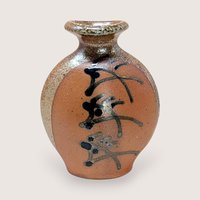 Vintage Brad Lee Henry studio pottery vase. Features a bulbous body in earthy red-brown with a metallic tenmoku drip glaze and black calligraphic slip-painted accents. 5 inches tall.