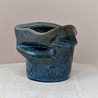 Vintage handmade studio pottery vase with an asymmetrical, pinched silhouette. Features a mottled deep blue and earth-toned glaze with a high-gloss finish. Signed on the base. 5 inches tall.