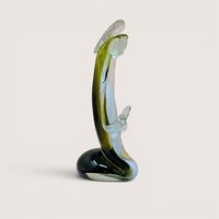 A vertical art glass sculpture of a person in a prayerful pose. A vibrant green inner layer is visible through the thick clear glass exterior, which curves into a stable, weighted base.