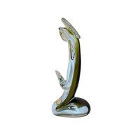 A handmade art glass figurine with a smooth, fluid silhouette. The piece features a vibrant emerald green core encased in a clear, glossy glass exterior. Its organic, elongated form tapers elegantly, reflecting light across its polished surface.