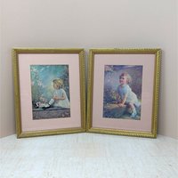 Pair of vintage 1930s framed prints by Zula Kenyon and Florence Lindsey. Features young girls in white dresses interacting with nature. Ornate gold wood frames with pink mats. 10.75 x 8.75 inches.