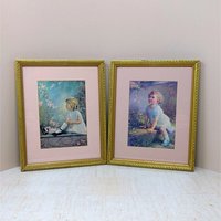 Pair of vintage 1930s framed prints by Zula Kenyon and Florence Lindsey. Features young girls in white dresses interacting with nature. Ornate gold wood frames with pink mats. 10.75 x 8.75 inches.