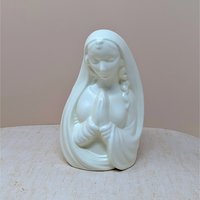 Mid-century white ceramic planter featuring a bust of a praying Madonna. Smooth, semi-matte ivory finish, flowing drapery, and serene facial expression. Hollow back for plants or stems.