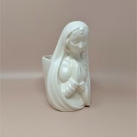Mid-century white ceramic planter featuring a bust of a praying Madonna. Smooth, semi-matte ivory finish, flowing drapery, and serene facial expression. Hollow back for plants or stems.