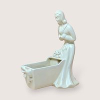Vintage Royal Haeger white pottery planter featuring a colonial-style woman in a flowing dress leaning over a baby cradle. High-gloss "Alabaster" white glaze. 11 inches tall.