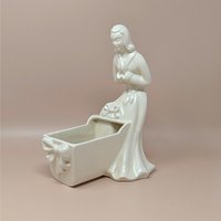 Vintage Royal Haeger white pottery planter featuring a colonial-style woman in a flowing dress leaning over a baby cradle. High-gloss "Alabaster" white glaze. 11 inches tall.