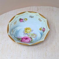 Scalloped octagonal porcelain bowl. Pale blue ombre interior with large pink and yellow roses. Wide rim features heavy gold gilt with a delicate beaded relief texture.