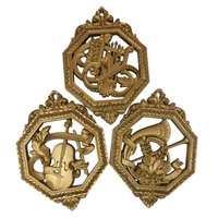 Set of three octagonal gold-toned wall plaques. Each features a different relief-style musical instrument: a lyre, a horn, and a violin. Ornate open-work frames with a metallic gilt finish.