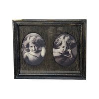 A dark wood frame with two oval cutouts. Inside are sepia-toned prints of a young child with curly hair and wings, depicting "Angel Awake" looking at the viewer and "Angel Asleep" with eyes closed. Rustic wood grain texture.