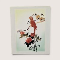 A vertical rectangular wall art piece featuring a bird perched on a branch, meticulously crafted from layered bamboo. Warm sienna and ochre tones are accented by deep red floral blooms. Framed with a clean white and pink double mat.
