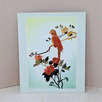 A vertical rectangular wall art piece featuring a bird perched on a branch, meticulously crafted from layered bamboo. Warm sienna and ochre tones are accented by deep red floral blooms. Framed with a clean white and pink double mat.