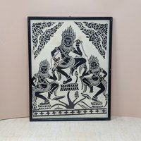 A vertical framed art piece on textured rice paper featuring three Apsara dancers in traditional Cambodian headdresses and poses. Bold black ink on a cream-white background. Framed in a minimalist black wood frame.