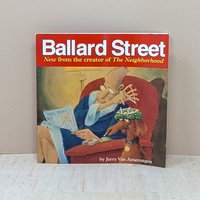A square paperback book titled "Ballard Street" in white text on a red bar. The cover art shows an elderly man in a blue robe sitting in a red armchair, tapping ashes into a hat worn by a dog. 144 pages of cartoon illustration.