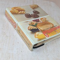 A vertical cookbook titled "Occident King Midas Collector's Bake Book." The cover features two panels of 1970s food photography showing pies, cakes, and breads. Orange and yellow "bubble" style typography.