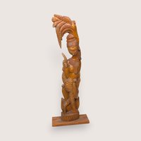 Ornate hand-carved vintage solid wood statue of a woman standing beneath a stylized palm leaf.