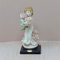 A finely detailed porcelain figurine of a young girl in a flowing white dress holding a large bouquet of pink roses. She stands on a dark wooden base with a gold Florence Giuseppe Armani plaque.