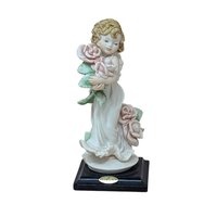 A finely detailed porcelain figurine of a young girl in a flowing white dress holding a large bouquet of pink roses. She stands on a dark wooden base with a gold Florence Giuseppe Armani plaque.