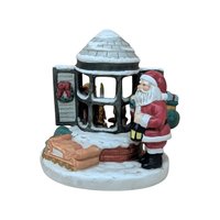 A painted ceramic music box featuring santa standing by a snowy bay window. A small child is visible inside the house through the panes. The colors are classic red, evergreen, and snowy white with a matte finish.