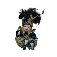A 12-inch porcelain baby doll dressed as a jester in emerald green velvet and gold brocade, featuring a large feathered jester hat and gold metallic ruff.