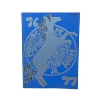 A vintage softcover yearbook with a bold blue cover. It features a large, silver-ink illustration of a rearing mustang horse centered over a circular school seal. The year 76-77 is printed in large block numbers.