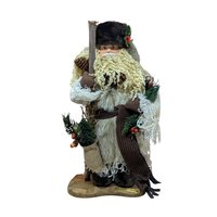 A tall, standing Father Christmas figure in a tan coat and brown fur hat. He has a long curly beard, holds a wooden staff, and carries a burlap sack with pine needles.