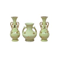 A collection of four vintage yellow ceramic vessels with bright gold accents. Includes a matching trio of Art Deco style vases with handles and gold leaf motifs, and a single rounded pitcher-style bud vase featuring a raised gold rose design.