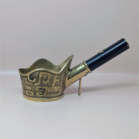 Brass silk iron with a long black wooden handle and ornate etched patterns on the vessel, shown on a neutral background.