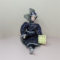A vintage Kingstate porcelain harlequin doll in a deep purple satin dress with silver lattice patterns and lace trim. She features hand-painted facial features and an ornate turban with a black mesh veil.