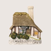 A 1993 David Winter "Crystal Cottage" miniature figurine featuring a detailed thatched roof, half-timbered walls, and a small stone bridge.