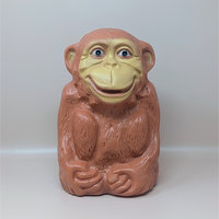 A large, light-brown molded plastic monkey bank with a tan face and a wide grin, standing against a neutral background.