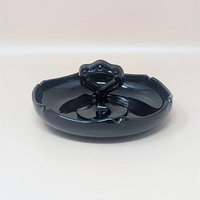 Glossy black amethyst glass trinket dish with a scalloped perimeter and a unique, ornate center handle featuring circular cutouts. The deep violet undertones are visible only under intense light.