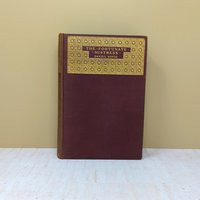 A plum-colored hardcover book with a large gold-stamped ornate panel on the front cover titled The Fortunate Mistress by Daniel Defoe against a neutral background.