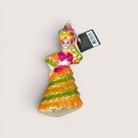 A vibrant vintage blown glass ornament of a dancer in a ruffled orange and lime green dress with a fruit basket headdress, still featuring its original Midwest tag.