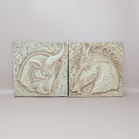 A pair of square vintage plaster wall plaques by Z. Danjell featuring stylized relief carvings of a horse and a bull in a Greek Brutalist style.