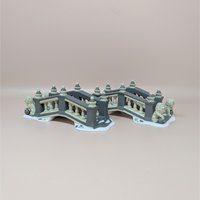 A pair of Department 56 Heritage Village ceramic bridges featuring grey and cream railings with miniature lion statues at the entrance on a snowy base.
